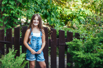 Little funny girl with long hair, portrait in a green park on a summer