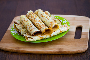 Pancakes rolls with cottage cheese on a wooden board. Pancakes with cheese. Shrovetide.