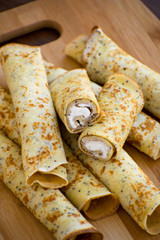 Pancakes rolls with cottage cheese on a wooden board. Pancakes with cheese. Shrovetide.