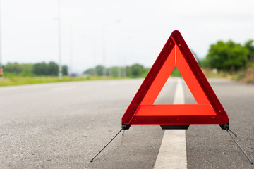 breakdown triangle symbol stands near broken car alongside the road. Car broke down on the road....