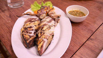 Grilled squid on dish with sauce.
