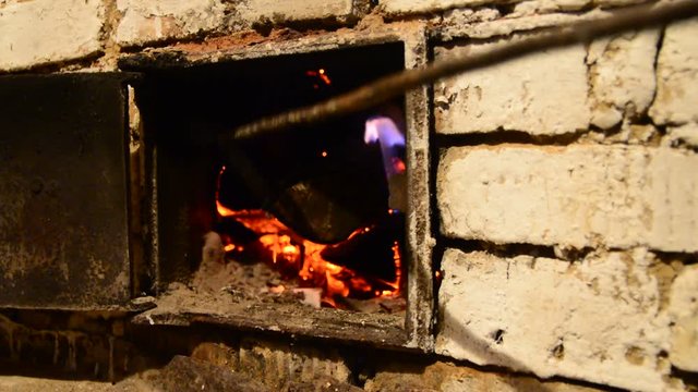 A man changes the place of burning firewood in the furnace
