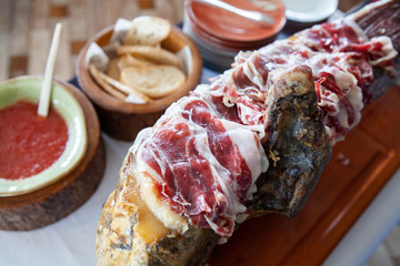 Top quality and delicious delicatessen, Spanish Jamon Iberico Ham made from Acorn Fed Black Iberian pigs. Sliced and placed on its leg with condiments. Italian Prosciutto Crudo or Parma ham.