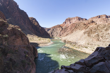 Early morning down the Grand Canyon at Bright Angel camp ground. The  suspension bridge over the Colorado river and the golden sunlight  hitting the mountains.