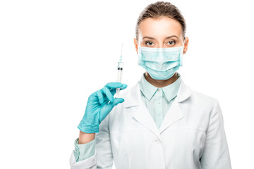 serious female doctor in medical mask holding syringe isolated on white