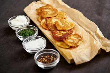 delicious potato pancakes and bowls with additions on an old wooden black table in the kitchen