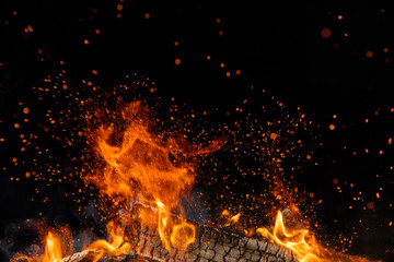 Brandende houten stammen in vuur, kampvuur op zwart