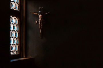 The crucifix, a cross with Jesus hanging on the wall, rays of light gently illuminate it