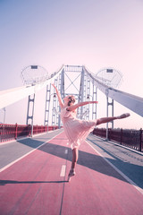 Beauty and plasticity. Beautiful flexible woman holding her leg up while dancing on the bridge © Viacheslav Yakobchuk
