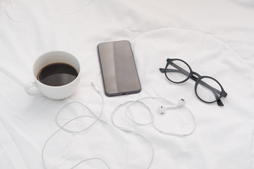 Smart phone on the bed with coffee cup.