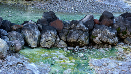 A natural Japanese outdoor sulphur sediment stone in steaming hot spring or on-sen pool.