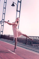 Such a beauty. Beautiful young woman holding a white flower while dancing on the bridge © Viacheslav Yakobchuk