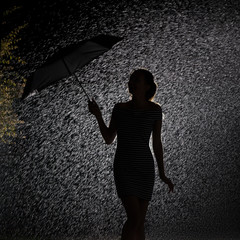silhouette of the figure of a young girl in the rain, happy young woman holding an umbrella that blows away