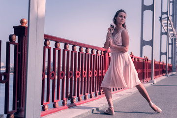 Tender beauty. Pleasant attractive ballerina standing with a flower while being on the bridge © Viacheslav Yakobchuk