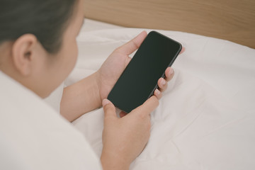 Woman sleeping and holding a mobile phone lying on the bed in bedroom