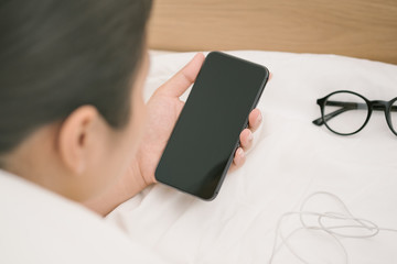 Woman sleeping and holding a mobile phone lying on the bed in bedroom