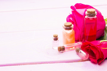 Spa and wellness setting with rose flower, sea salt, oil in a bottle on wooden white background