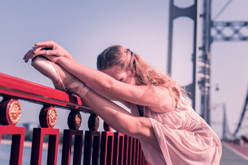 Before dancing. Nice young woman touching her leg while warming up near the parapet © Viacheslav Yakobchuk