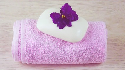 Pink towel and soap with floral scent on light background.