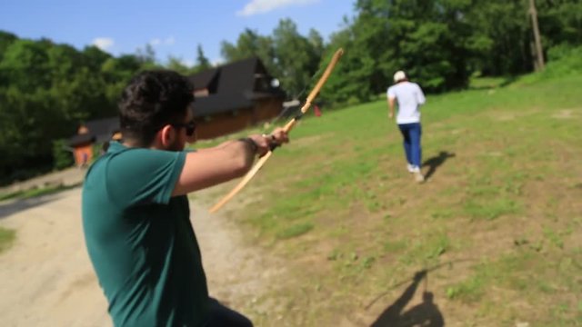 Young man shoots an arrow from a bow