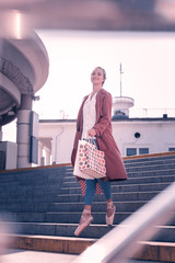 Successful shopping. Positive nice woman holding shopping bag while going from the shop © Viacheslav Yakobchuk