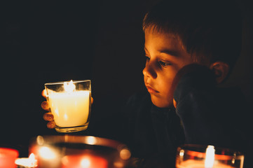 Child in the dark looks at candles