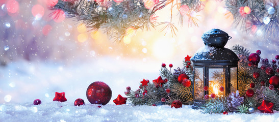 Weihnachtslaterne auf Schnee mit Tannenzweig im Sonnenlicht. Winterdekoration Hintergrund