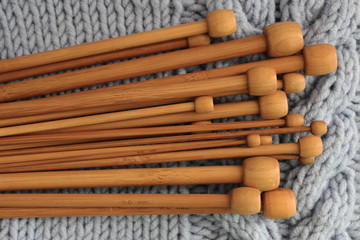 Wooden knitting needles on blue knitted background. The concept of Hobbies and crafts.
