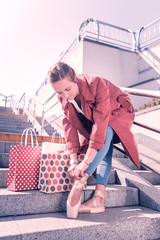 Modern consumerism. Pleasant female dancer standing near her shopping bags while tying up her pointe shoes © Viacheslav Yakobchuk