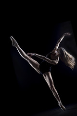 In the photo studio a young ballerina with a beautiful body dances.