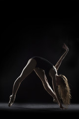 Fototapeta na wymiar In the photo studio a young ballerina with a beautiful body dances.