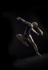 Fototapeta na wymiar In the photo studio a young ballerina with a beautiful body dances.