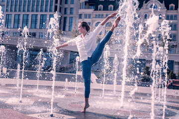 Professional ballerina. Attractive female dancer holding her leg up while dancing in the fountain © Viacheslav Yakobchuk