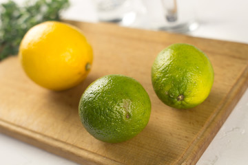 Fresh lemon and lime on wood surface and glass in kitchen. Close up.