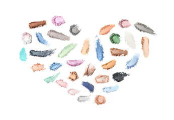 Creative set with different makeup product smears in shape of heart on white background