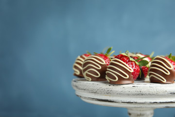 Dessert stand with chocolate covered strawberries on color background, closeup