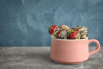 Cup with chocolate covered strawberries on table