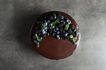Fresh delicious homemade chocolate cake with berries on gray table, top view