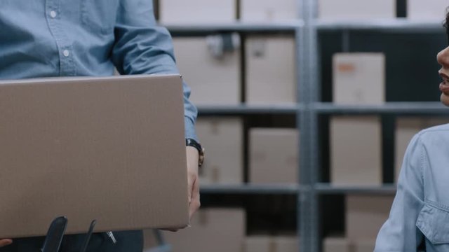 Female Inventory Manager Scans Cardboard Box with Barcode Scanner, Worker Puts Package on the Designated Shelf. In the Background Rows of Cardboard Boxes with Products Ready For Shipment.