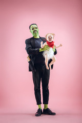 Halloween Family. Happy Father and Children Newborn Girl in Halloween Costume and Makeup. Bloody theme: the crazy maniak on pink studio background