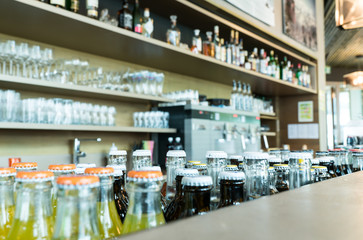 selective focus of a many drinks and beverages on and behind a stylish bar and lounge with coffee machine and bottles and glasses