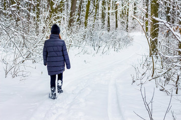A young girl goes on a forest road in winter, an active rest_