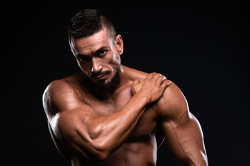 Fototapeta na wymiar Muscular fitness burnet man is showing bicep putting is hand on the shoulder