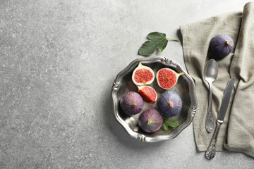 Dish with fresh ripe figs on gray background, top view. Space for text