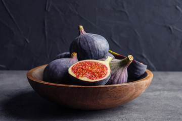 Bowl with fresh ripe figs on gray table. Tropical fruit