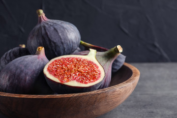 Bowl with fresh ripe figs on gray table. Tropical fruit