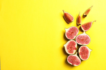 Cut ripe figs on color background, top view. Space for text
