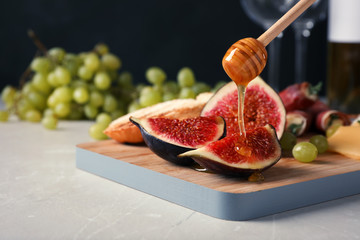 Pouring honey onto ripe fig slices on wooden board, closeup