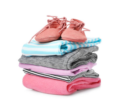 Children's shoes and stack of clothes on white background