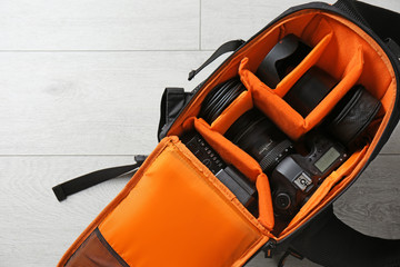 Naklejka premium Bag with digital camera on floor. Professional photographer's equipment